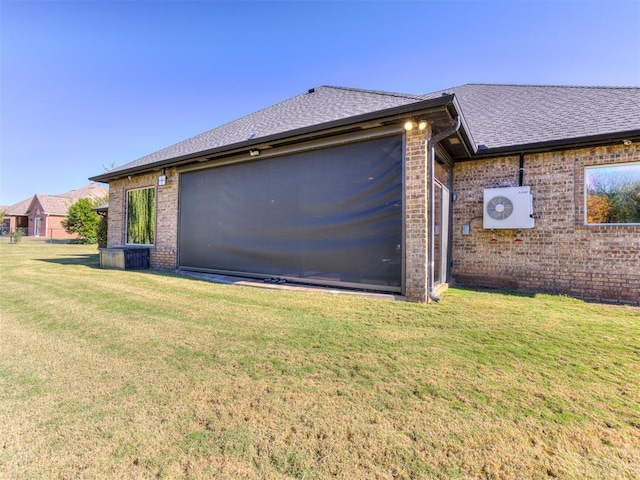 view of side of home with a shingled roof, a lawn, and brick siding