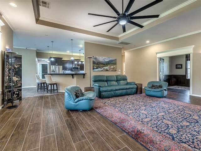 living area featuring crown molding, a raised ceiling, visible vents, and wood tiled floor