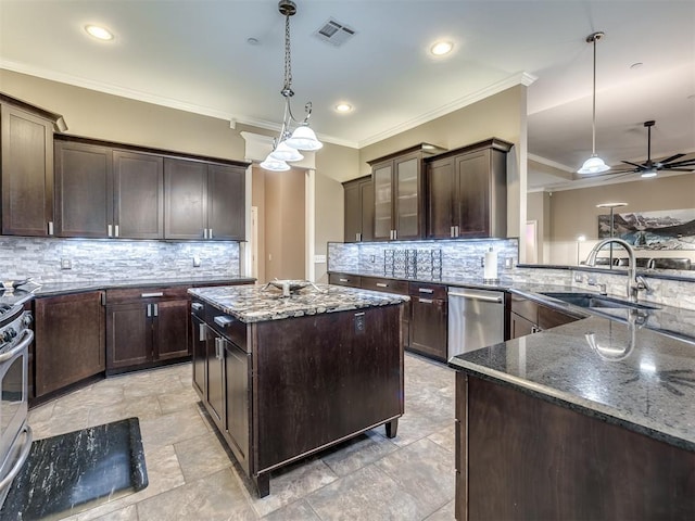 kitchen featuring dark brown cabinetry, stainless steel appliances, a sink, visible vents, and dark stone counters