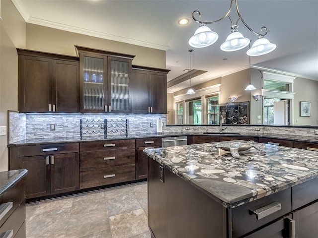 kitchen with dark stone counters, ornamental molding, backsplash, and dark brown cabinetry