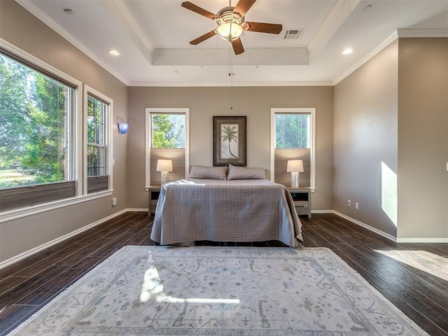 unfurnished bedroom with a tray ceiling, multiple windows, wood finished floors, and visible vents