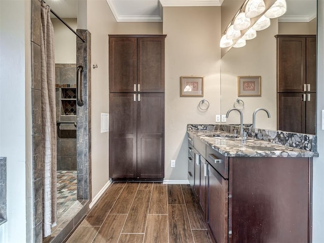 bathroom featuring crown molding, wood tiled floor, a tile shower, vanity, and baseboards