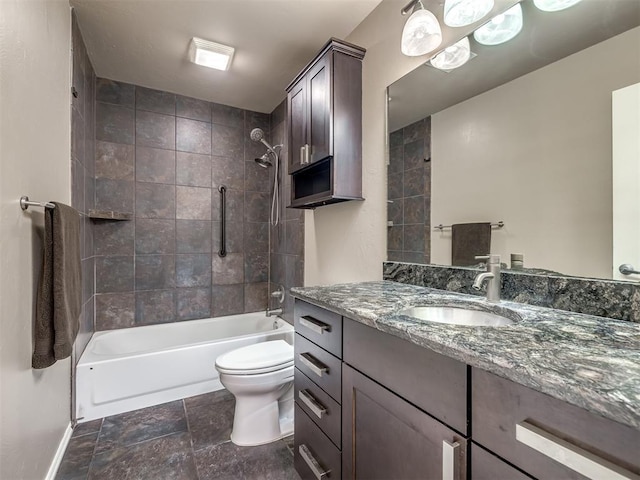 full bathroom featuring baseboards, toilet, vanity, stone finish flooring, and shower / bathtub combination