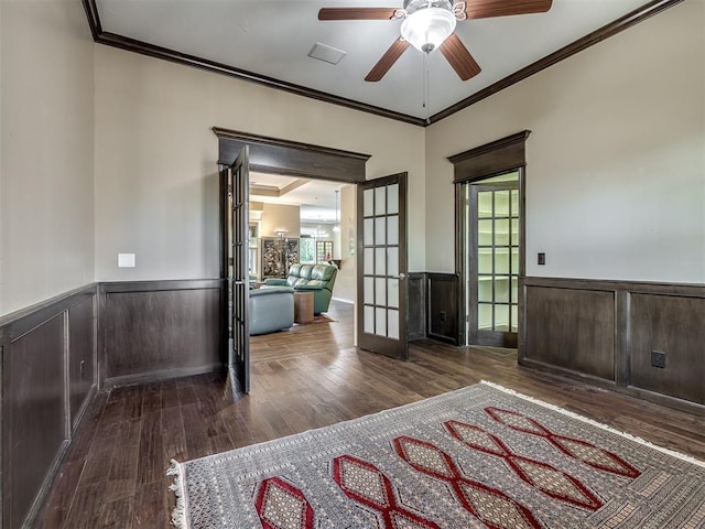 interior space featuring a wainscoted wall, crown molding, wood finished floors, and french doors