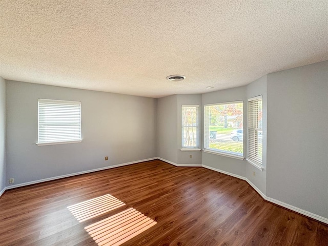 spare room featuring wood-type flooring and a textured ceiling