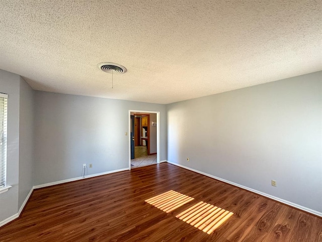 unfurnished room with a textured ceiling and hardwood / wood-style flooring