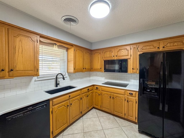 kitchen with sink, tasteful backsplash, a textured ceiling, light tile patterned floors, and black appliances