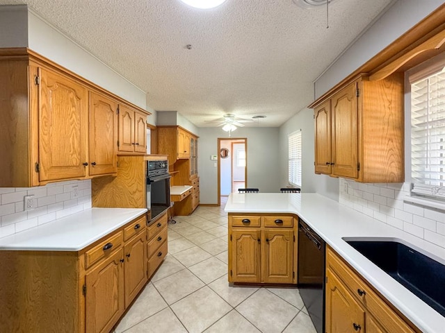 kitchen with kitchen peninsula, decorative backsplash, sink, black appliances, and light tile patterned floors