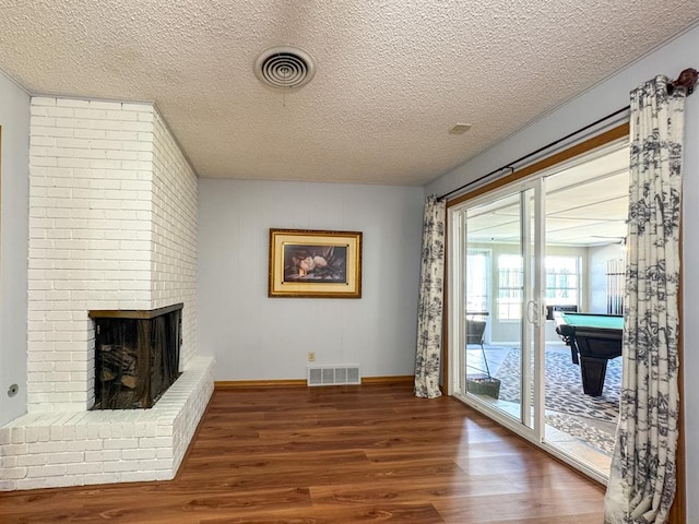 living room featuring a textured ceiling, dark hardwood / wood-style floors, and a fireplace