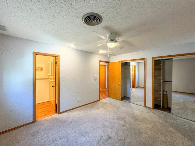 unfurnished bedroom with a textured ceiling, ensuite bathroom, ceiling fan, and light colored carpet