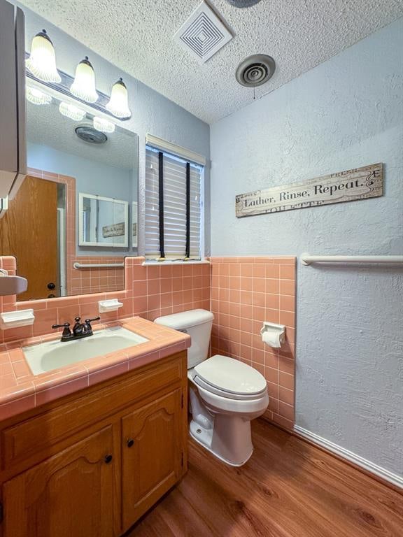 bathroom with tile walls, toilet, a textured ceiling, and hardwood / wood-style flooring