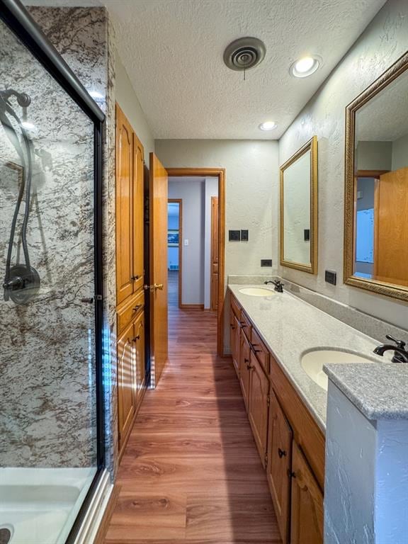 bathroom featuring hardwood / wood-style flooring, vanity, a shower, and a textured ceiling