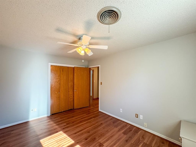 unfurnished bedroom with hardwood / wood-style floors, ceiling fan, a textured ceiling, and a closet