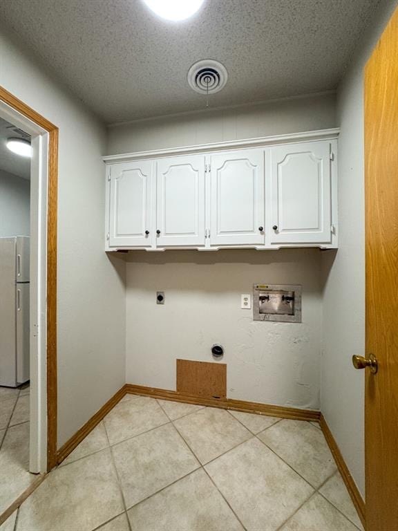 laundry room with hookup for an electric dryer, hookup for a washing machine, a textured ceiling, and light tile patterned flooring