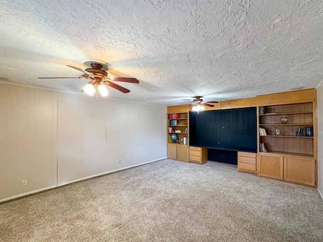 unfurnished living room with carpet, ceiling fan, built in desk, and a textured ceiling