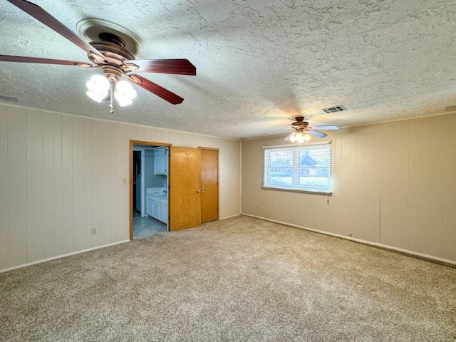 unfurnished bedroom featuring connected bathroom, ceiling fan, light colored carpet, and a textured ceiling