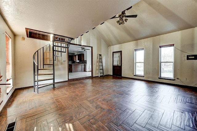 unfurnished living room featuring dark parquet flooring, a textured ceiling, ceiling fan, and lofted ceiling