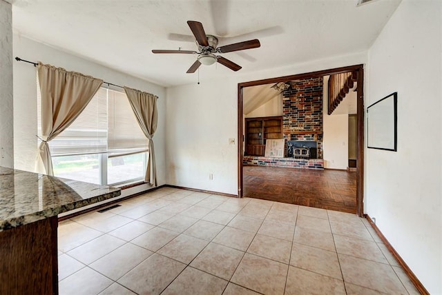 interior space featuring a wood stove, ceiling fan, and light tile patterned flooring