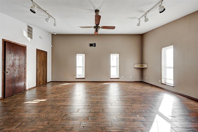 empty room with a healthy amount of sunlight, dark hardwood / wood-style flooring, and rail lighting