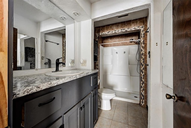 bathroom with tile patterned flooring, vanity, toilet, and a shower