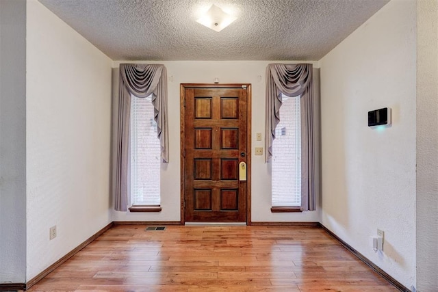 foyer featuring a textured ceiling, light wood-type flooring, and plenty of natural light