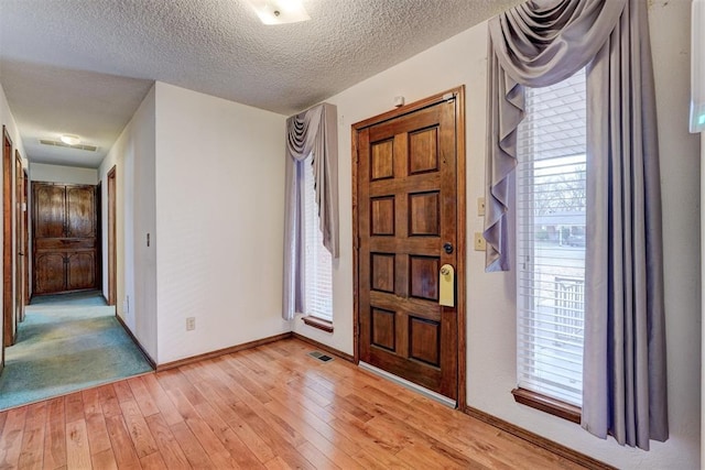 foyer featuring light hardwood / wood-style flooring and a textured ceiling