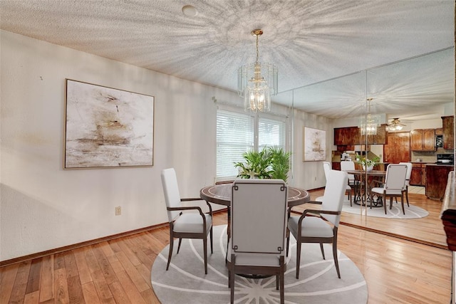 dining area with a chandelier, a textured ceiling, and light wood-type flooring