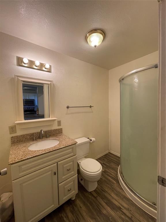 bathroom featuring an enclosed shower, vanity, a textured ceiling, wood-type flooring, and toilet