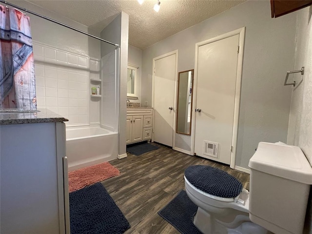 full bathroom with vanity, shower / washtub combination, toilet, a textured ceiling, and wood-type flooring