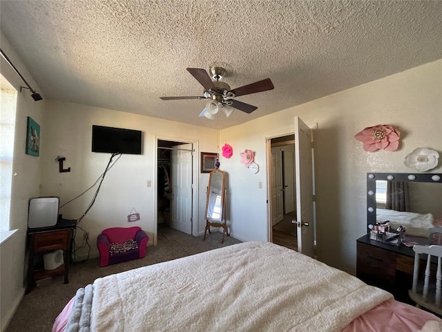 bedroom with ceiling fan, dark carpet, a textured ceiling, and a closet