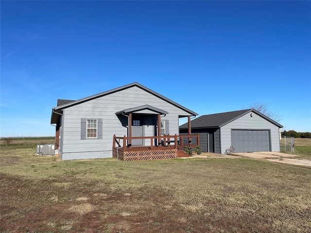 view of front of home featuring a garage, a deck, an outbuilding, and a front lawn