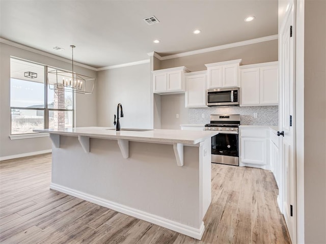 kitchen with white cabinets, an island with sink, stainless steel appliances, and sink