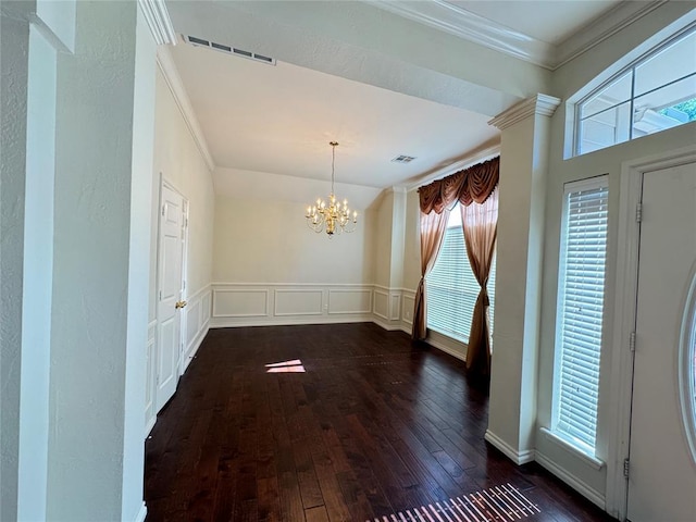 unfurnished dining area featuring dark hardwood / wood-style flooring, a notable chandelier, and ornamental molding