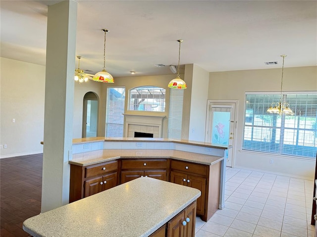 kitchen featuring a fireplace, light tile patterned floors, ceiling fan with notable chandelier, and decorative light fixtures