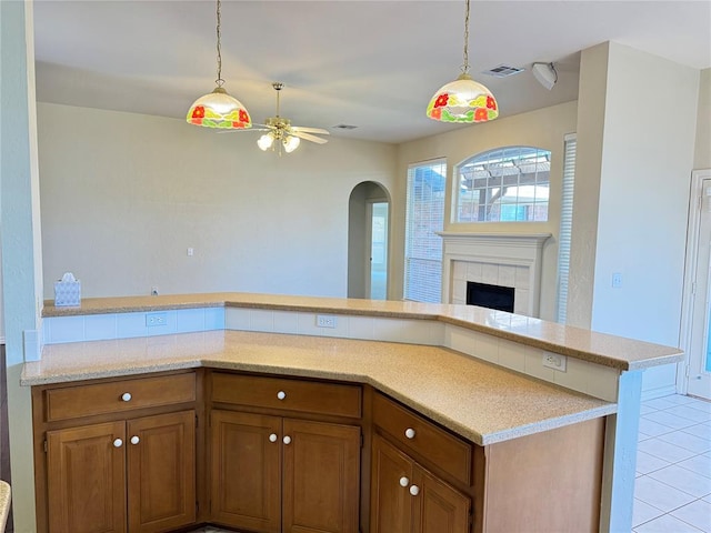 kitchen featuring a tile fireplace, light tile patterned floors, and ceiling fan