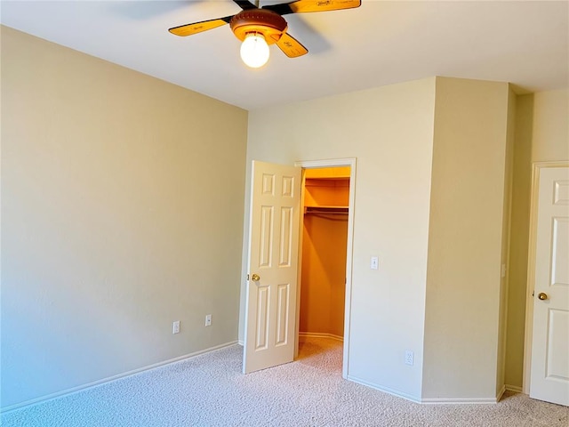 unfurnished bedroom featuring ceiling fan, a closet, light colored carpet, and a spacious closet