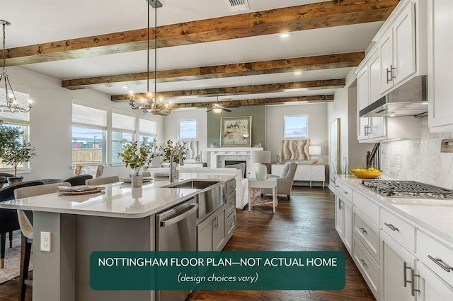 kitchen with appliances with stainless steel finishes, a kitchen breakfast bar, a center island with sink, white cabinetry, and hanging light fixtures