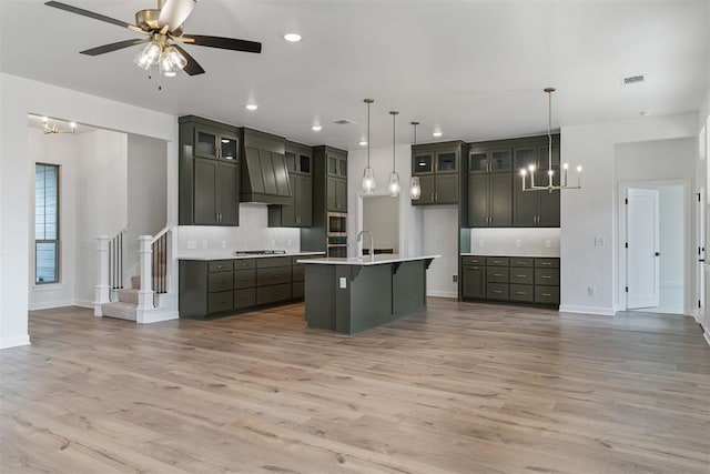 729 Caladium Dr, Yukon, OK 73099 - kitchen with glass insert cabinets, premium range hood, light countertops, light wood-style floors, and a sink