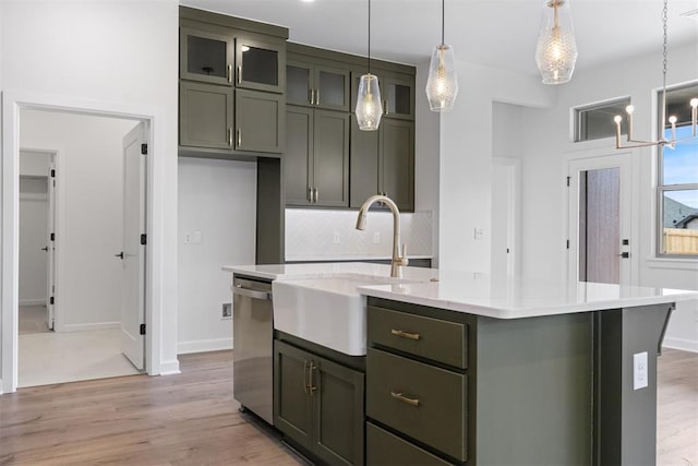 729 Caladium Dr, Yukon, OK 73099 - kitchen with a kitchen island with sink, light countertops, light wood-style floors, stainless steel dishwasher, and backsplash
