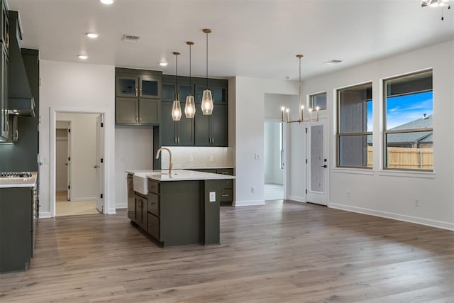 729 Caladium Dr, Yukon, OK 73099 - kitchen with a sink, tasteful backsplash, wood finished floors, an inviting chandelier, and light countertops