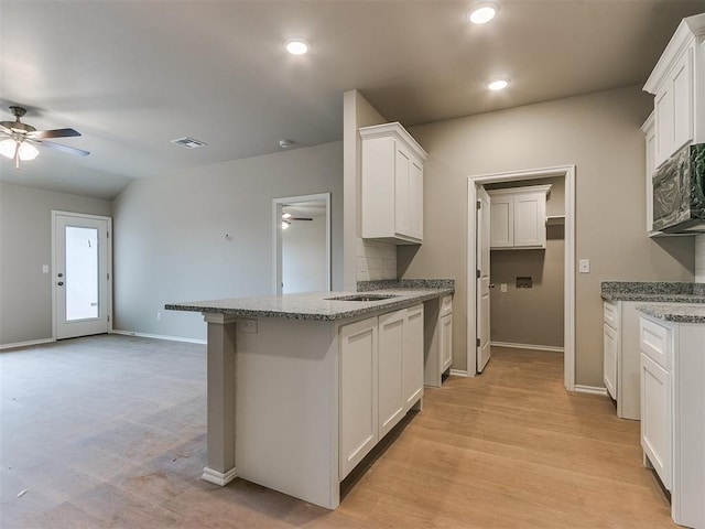 kitchen with visible vents, white cabinets, ceiling fan, stainless steel microwave, and a peninsula