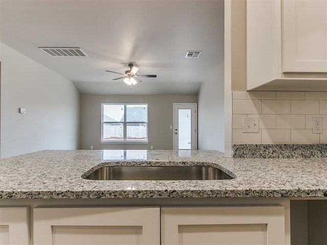 kitchen with light stone counters, tasteful backsplash, and visible vents