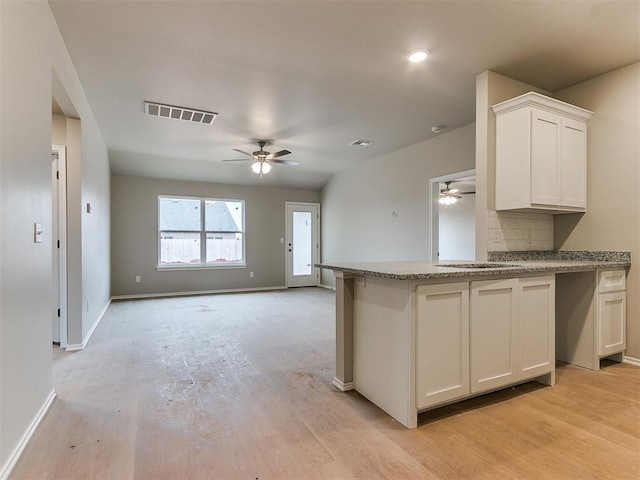 kitchen featuring a ceiling fan, white cabinets, visible vents, and backsplash