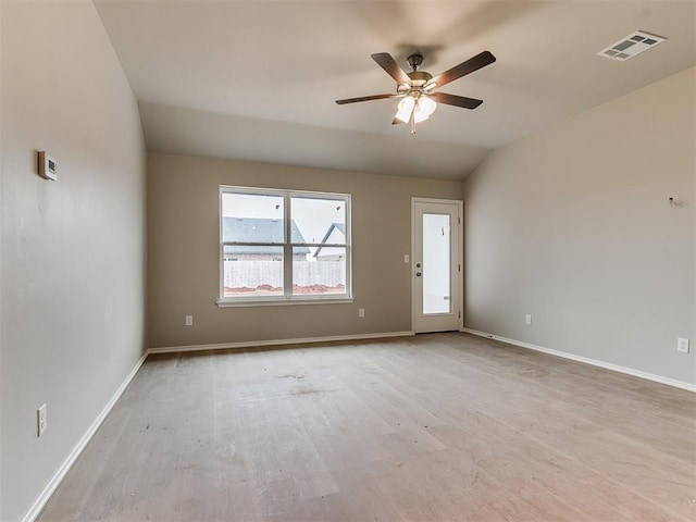 spare room featuring baseboards, visible vents, a ceiling fan, wood finished floors, and vaulted ceiling