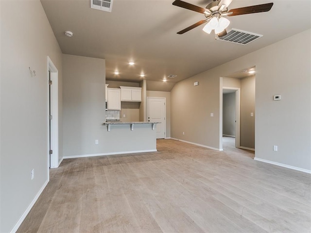 unfurnished living room featuring light wood-style floors, baseboards, visible vents, and a ceiling fan