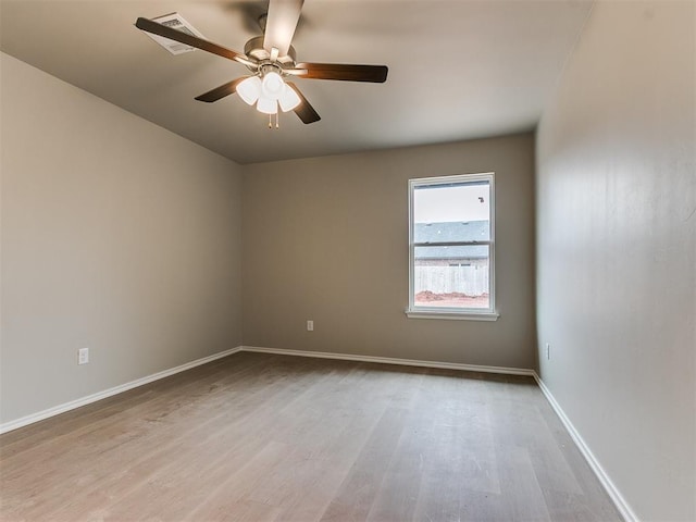 spare room featuring wood finished floors, a ceiling fan, and baseboards