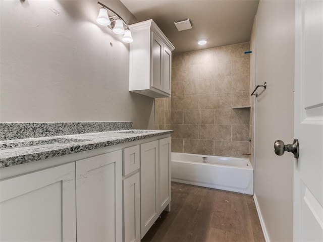 bathroom featuring vanity, baseboards, wood finished floors, and shower / bathing tub combination