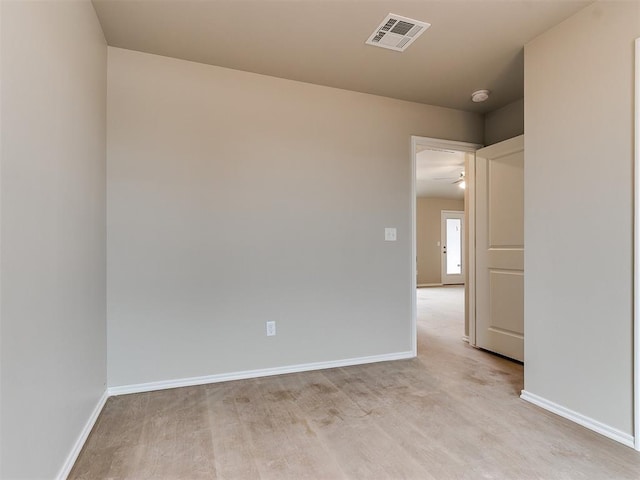 empty room featuring light wood-style flooring, visible vents, and baseboards