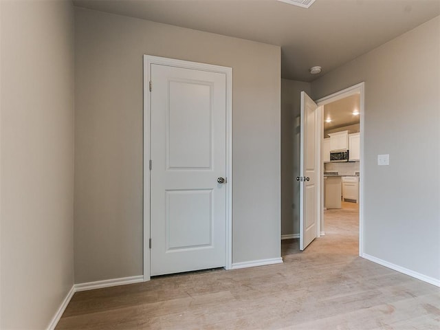 unfurnished bedroom featuring light wood finished floors and baseboards