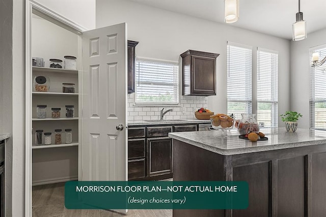 kitchen with sink, hanging light fixtures, hardwood / wood-style floors, decorative backsplash, and dark brown cabinets